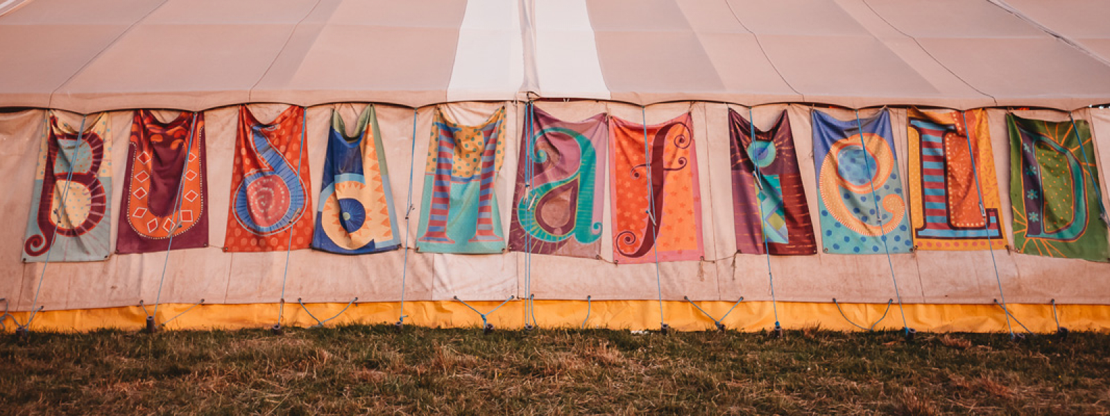 Flags on the side of a tent that spell out Buddhafield